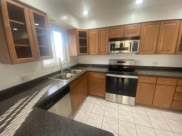 kitchen with brown cabinets, glass insert cabinets, appliances with stainless steel finishes, and a sink