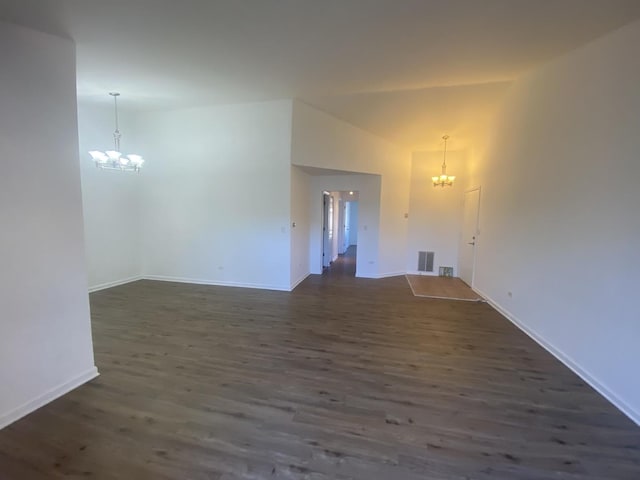 unfurnished living room with an inviting chandelier, dark wood-type flooring, and visible vents