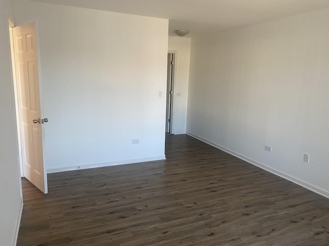 unfurnished room featuring baseboards and dark wood finished floors