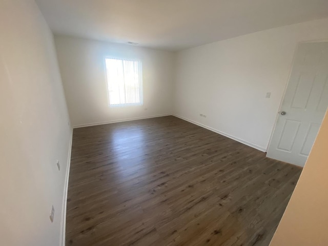 spare room with dark wood finished floors and baseboards