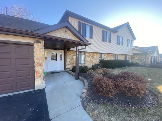 split level home with an attached garage and stone siding