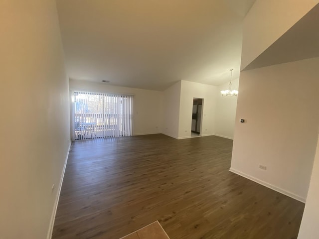 unfurnished room featuring baseboards, an inviting chandelier, dark wood-style flooring, and vaulted ceiling
