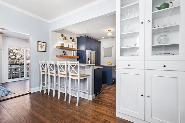 kitchen with open shelves, dark wood-style flooring, ornamental molding, a kitchen bar, and stainless steel fridge