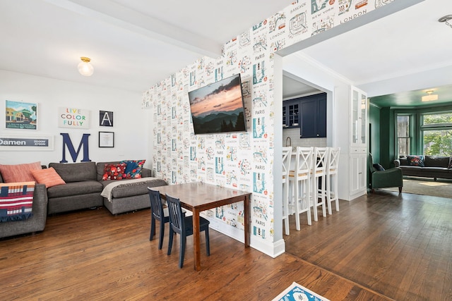 living area with baseboards, beamed ceiling, wood finished floors, and wallpapered walls