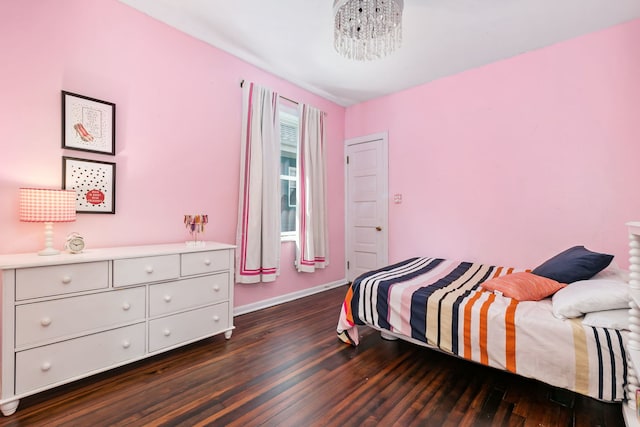 bedroom featuring baseboards, dark wood finished floors, and a notable chandelier
