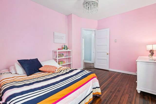 bedroom featuring an inviting chandelier, baseboards, and wood finished floors