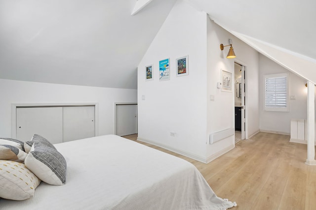 bedroom with light wood-type flooring, baseboards, multiple closets, and lofted ceiling