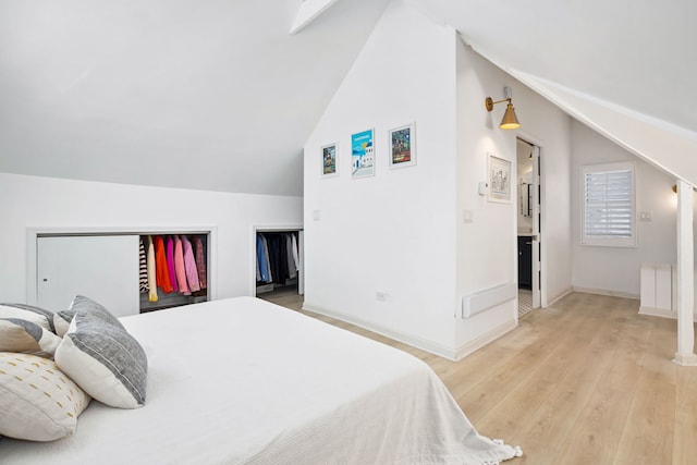 bedroom featuring baseboards, light wood-type flooring, and lofted ceiling