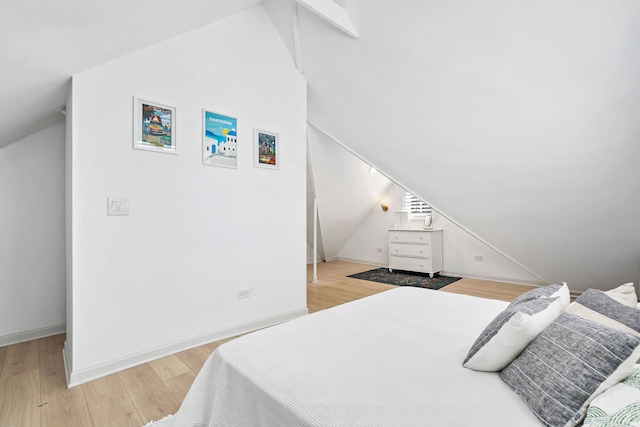bedroom with light wood-style floors, baseboards, and vaulted ceiling