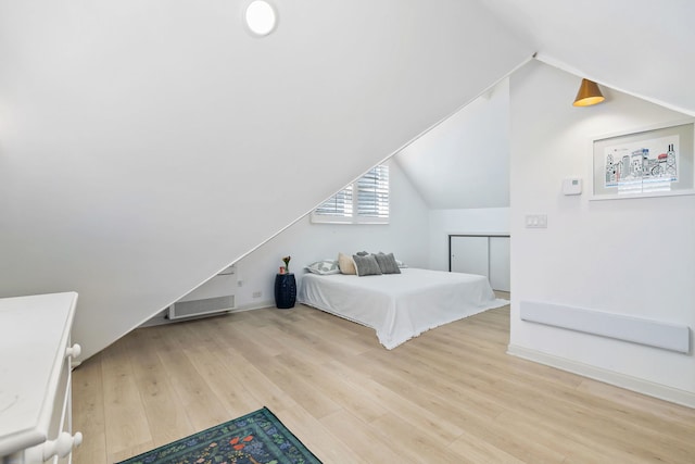 bedroom featuring baseboards, vaulted ceiling, wood finished floors, and visible vents