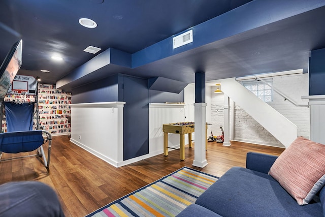 interior space featuring stairs, brick wall, visible vents, and wood finished floors