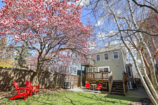 back of property with a lawn, a deck, a patio area, a fenced backyard, and stairs