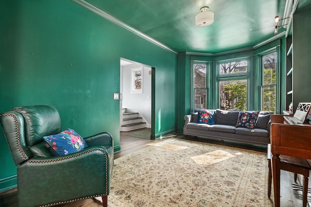 sitting room with baseboards, ornamental molding, wood finished floors, and stairway