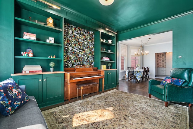 living room featuring a notable chandelier, built in features, dark wood-type flooring, visible vents, and ornamental molding