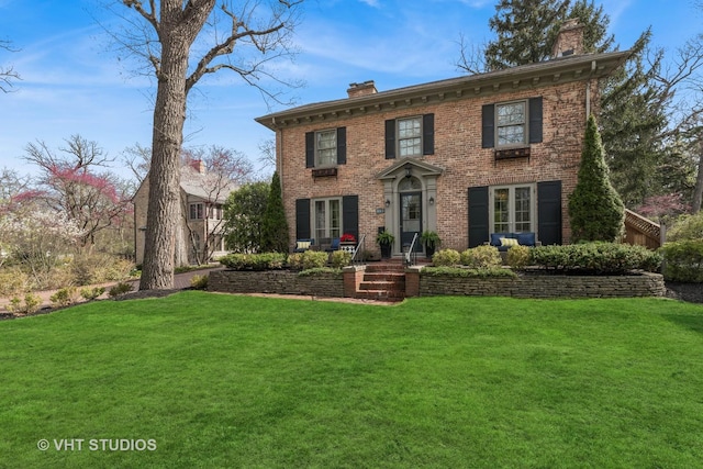 view of front of property with a chimney, brick siding, and a front lawn