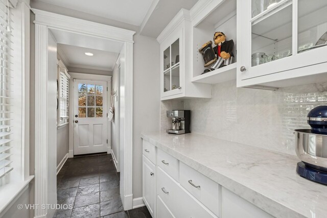 bar area featuring stone tile floors, backsplash, baseboards, crown molding, and recessed lighting