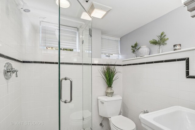full bathroom featuring tile walls, a shower stall, and toilet