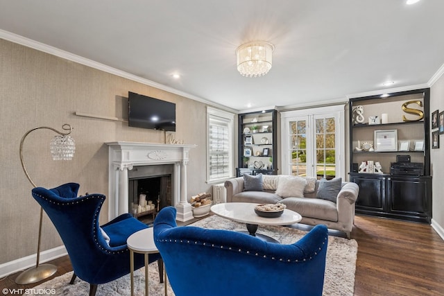 living area with ornamental molding, baseboards, wood finished floors, a fireplace, and a chandelier