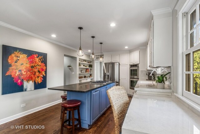 kitchen with blue cabinets, stainless steel appliances, a kitchen island, crown molding, and white cabinets