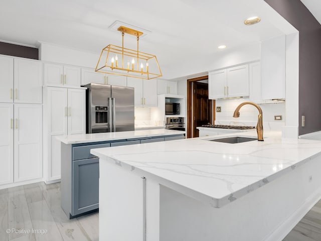 kitchen featuring white cabinets, a peninsula, light stone countertops, and appliances with stainless steel finishes