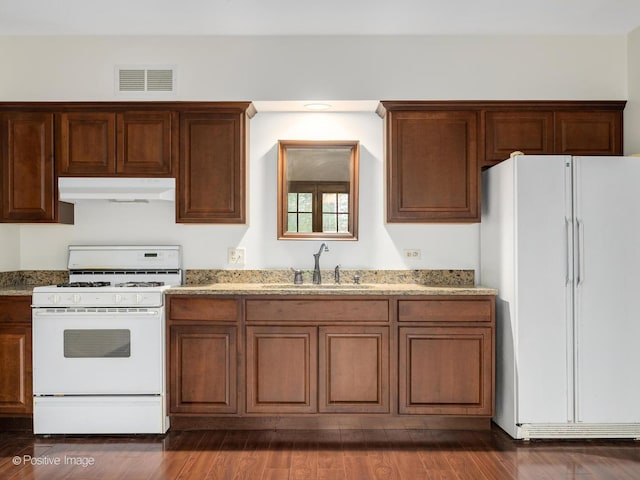 kitchen with visible vents, white appliances, light stone countertops, under cabinet range hood, and a sink