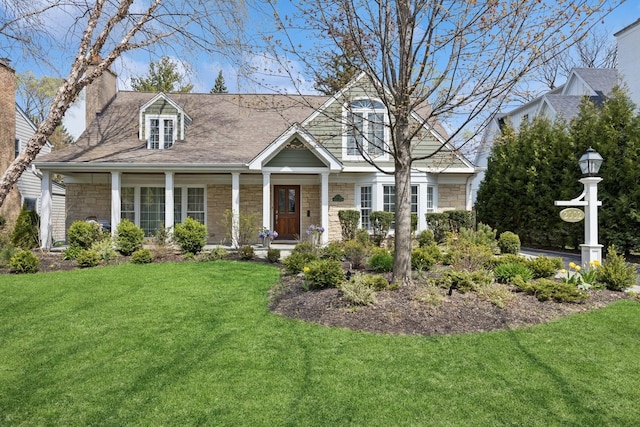 cape cod house with a chimney, a front yard, and stone siding