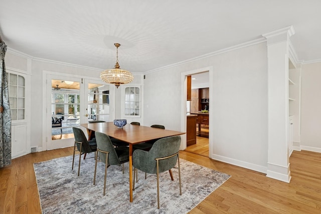 dining room with baseboards, an inviting chandelier, ornamental molding, and light wood-style floors