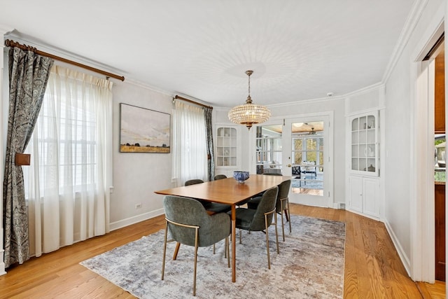 dining space featuring crown molding, baseboards, light wood finished floors, and a chandelier