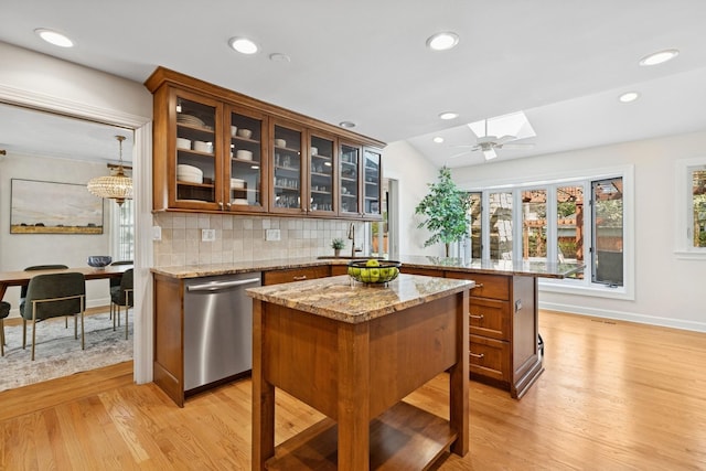 kitchen featuring dishwasher, light wood-style flooring, baseboards, backsplash, and glass insert cabinets