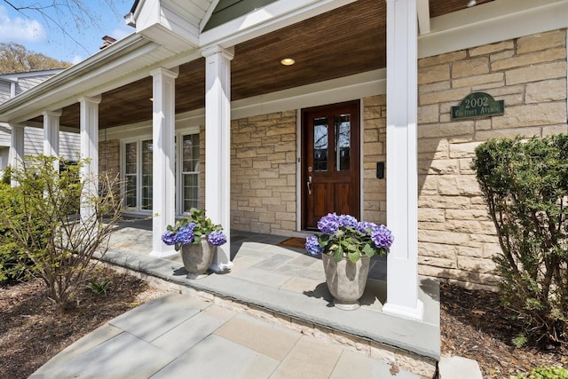 doorway to property featuring covered porch and stone siding