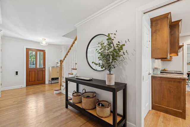 entrance foyer with stairs, baseboards, ornamental molding, and light wood-style floors