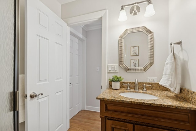 bathroom with vanity, ornamental molding, and wood finished floors