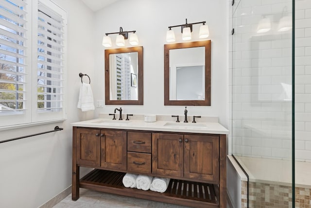 full bath with a sink, baseboards, double vanity, and tiled shower