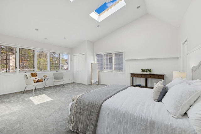 bedroom featuring carpet flooring, wainscoting, high vaulted ceiling, a skylight, and a closet