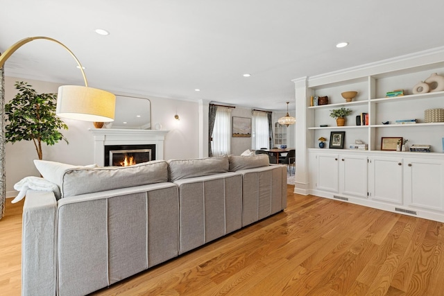 living room with recessed lighting, a glass covered fireplace, visible vents, and light wood-style floors