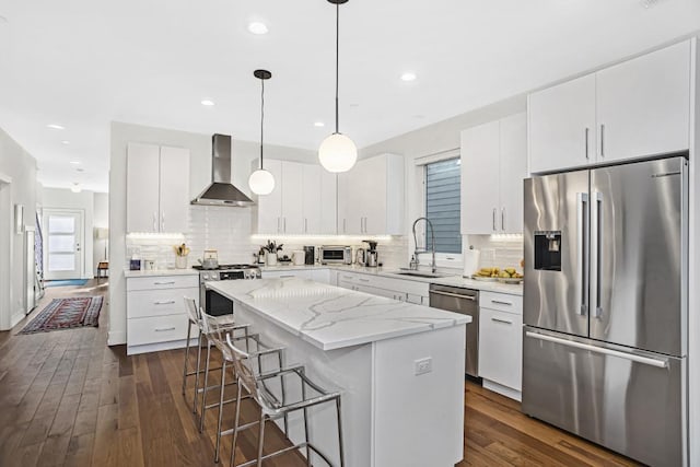1122 Pitner Ave, Evanston, IL 60202 - kitchen featuring appliances with stainless steel finishes, wall chimney exhaust hood, a kitchen island, a kitchen bar, and tasteful backsplash