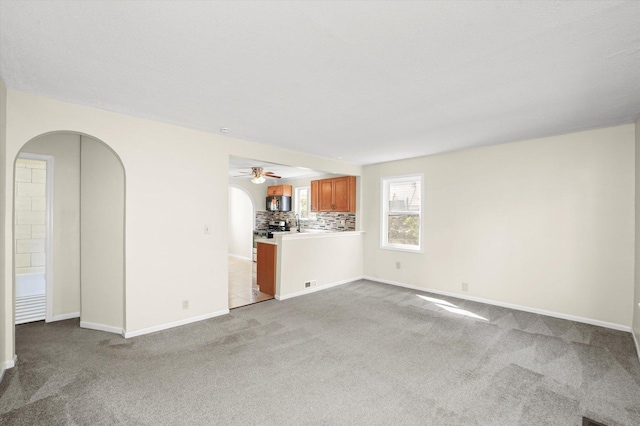 15 N Hillcrest Ave, Fox Lake, IL 60020 - unfurnished living room featuring arched walkways, baseboards, light carpet, and ceiling fan