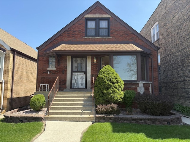 view of front of home featuring brick siding and roof with shingles