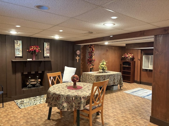 dining space with wooden walls, parquet flooring, and a paneled ceiling