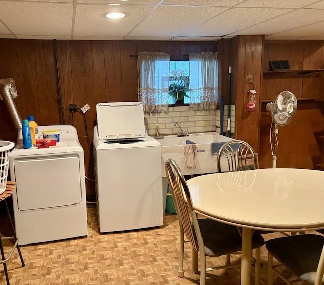 laundry area with separate washer and dryer, laundry area, wood walls, and a sink