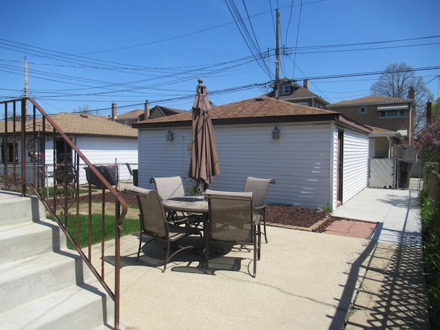 view of patio featuring fence, a detached garage, and a gate