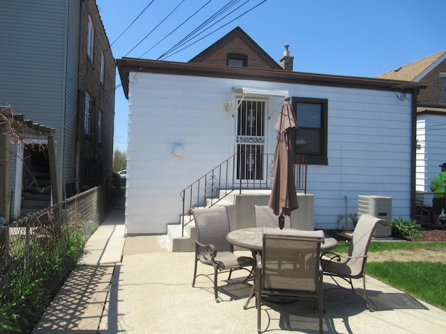 rear view of house with a patio, fence, central air condition unit, and outdoor dining space