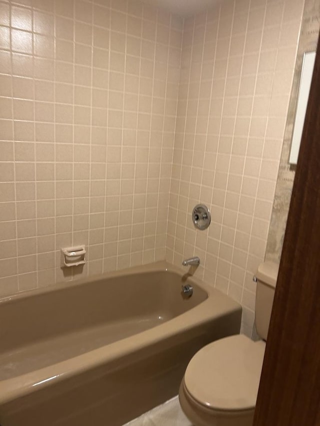 bathroom featuring toilet, shower / bath combination, and tile walls