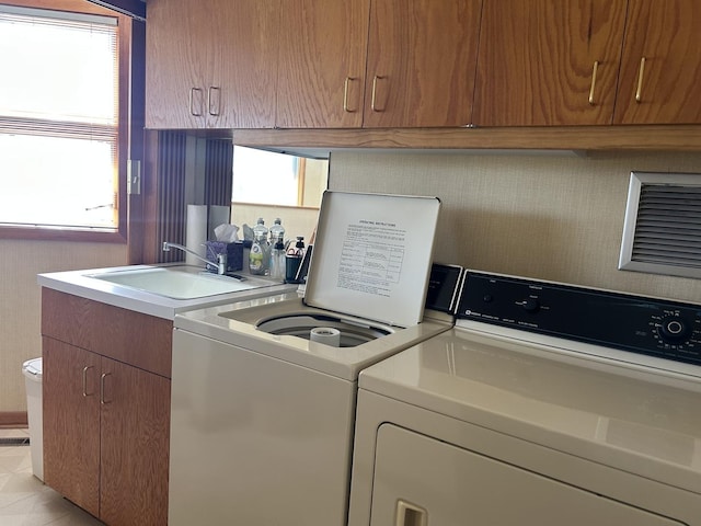 laundry area featuring washer and dryer, a sink, laundry area, and a healthy amount of sunlight