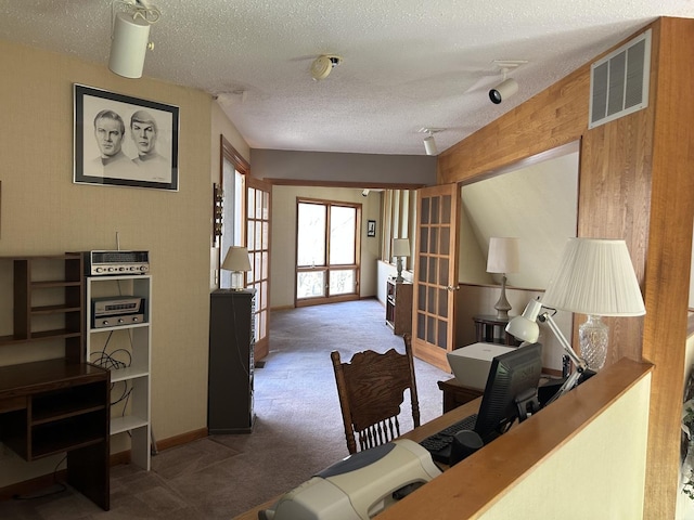 carpeted home office with a textured ceiling and visible vents