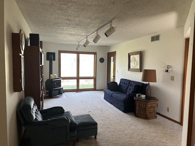 carpeted living area featuring baseboards, visible vents, and a textured ceiling