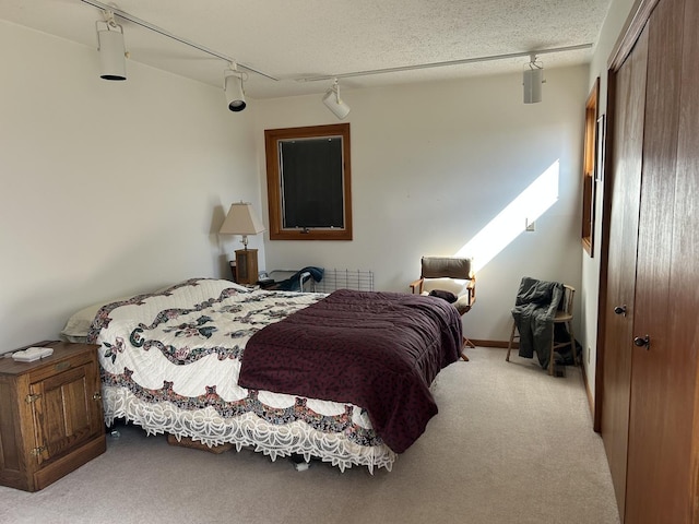 carpeted bedroom featuring ceiling fan, rail lighting, and a closet