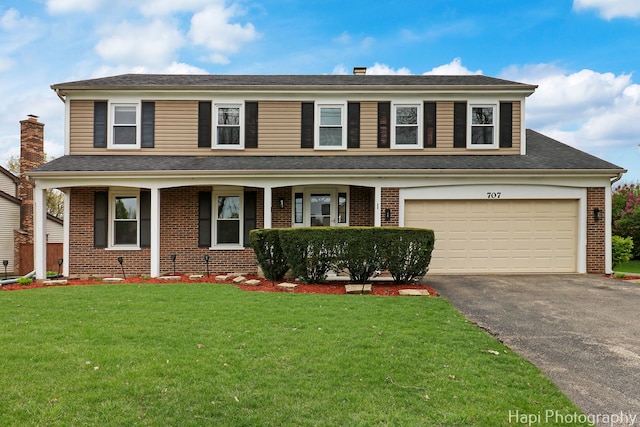 view of front of property featuring brick siding, driveway, a front yard, a garage, and covered porch