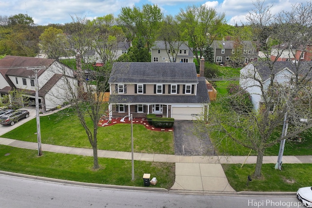 view of front facade featuring a residential view, asphalt driveway, a front yard, and a chimney