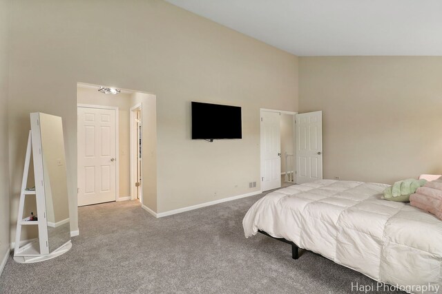 carpeted bedroom featuring high vaulted ceiling and baseboards